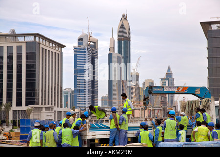 Asian operai sul sito all'incompiuta, incompleta grattacielo edifici; stranieri immigrati progetto di costruzione i lavoratori a costruire il nuovo Dubai. Emirati arabi uniti Foto Stock