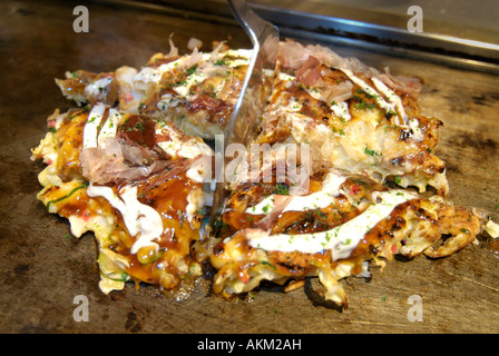 Okonomi yaki stile giapponese gustosi pancake cotti su una piastra calda Giappone Foto Stock