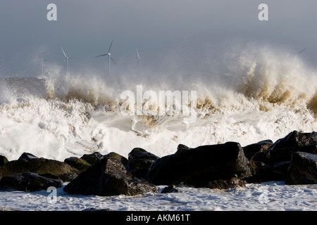 Onde si infrangono sugli scogli a Great Yarmouth durante la tempesta di vento di forza, con offshore wind farm in distanza Foto Stock