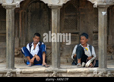 Due uomini Nepalese prendendo una pausa all'ombra di un tempio Patan Kathmandu in Nepal Foto Stock