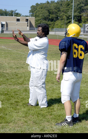 Alta Scuola Calcio azione Port Huron Michigan sordi JV giocatore di football legge la lingua dei segni data dal nero aiuto durante la pratica Foto Stock