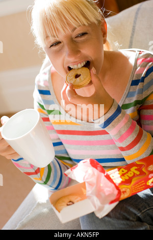 Donna di mangiare i biscotti con bevanda Foto Stock