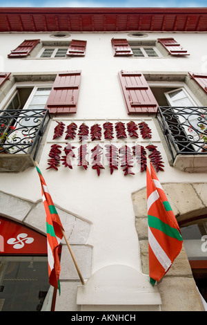 In Espelette peperoni, appendere fuori su una tipica casa basco anteriore (Francia). Facciata de maison et piments suspendus (Francia). Foto Stock