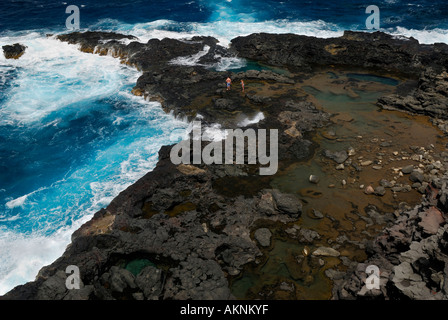 Rocce laviche e soffiare il foro con le persone al punto Mokolea sulla costa di Maui Hawaii Foto Stock