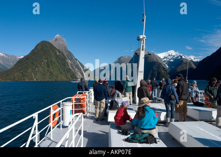 I turisti sul ponte di una nave da crociera con Mitre Peak dietro, Milford Sound, Parco Nazionale di Fiordland, Isola del Sud, Nuova Zelanda Foto Stock