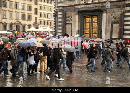 I turisti a piedi sotto la pioggia e il Battistero, vicino al Duomo di Firenze Foto Stock
