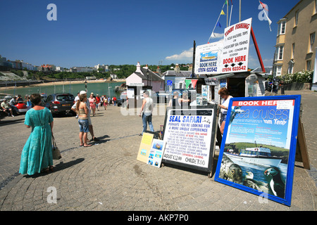 Piccole imprese locali tentano di attirare il passaggio di traffico turistico su gite in barca Tenby harbour Pembrokeshire West Wales UK Foto Stock