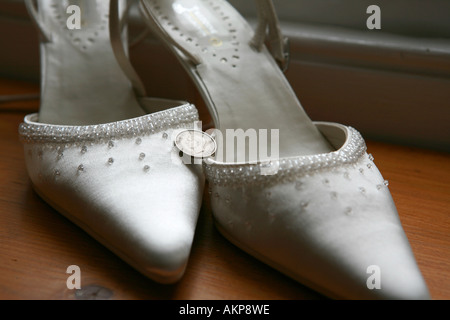 Primo piano dettaglio di una speciale spose il giorno del nostro matrimonio con tacco alto costoso scarpe con buona fortuna portafortuna sei pence coin Foto Stock