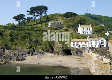 Turisti a piedi English villaggio porto parete accanto spiaggia costiera sotto Cornish collina cottage in River Pol Valley Polperro Cornwall Inghilterra Regno Unito Foto Stock