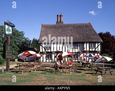 Clienti al di fuori del tetto di paglia Royal Oak mezzo legno nero e bianco villaggio pub posti a sedere panca all'aperto e ombrellone Barrington Cambridgeshire Inghilterra Regno Unito Foto Stock