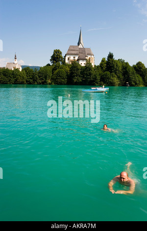 La gente di nuoto nel Worthersee Chiesa Parrocchiale e la Chiesa del Rosario Maria vale la pena di Carinzia Austria Foto Stock