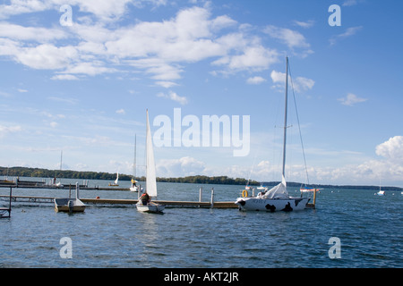 Barche a vela su un ampio corpo di acqua sotto un cielo blu con nuvole bianche a un dock. Foto Stock