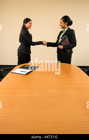 Due imprenditrici nelle tute agitando mani e sorridente Foto Stock