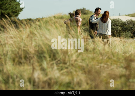 Gruppo di amici a piedi attraverso le dune, vista posteriore Foto Stock