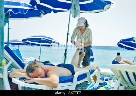 Nizza Francia 'Beach Scene' 'donna cinese" dando massaggi ai turisti sulla spiaggia in vacanza rilassante Foto Stock