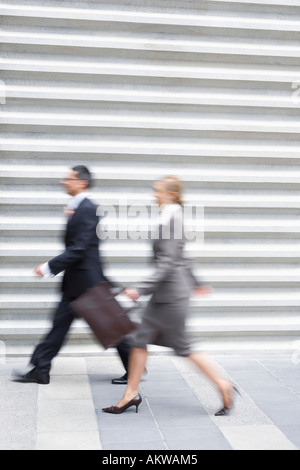 Imprenditore e imprenditrice camminare velocemente, vista laterale Foto Stock