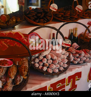 Display a colori di piccante carni e insaccati in cesti di vimini con bottiglie di vino sul mercato in stallo il sud della Francia Foto Stock