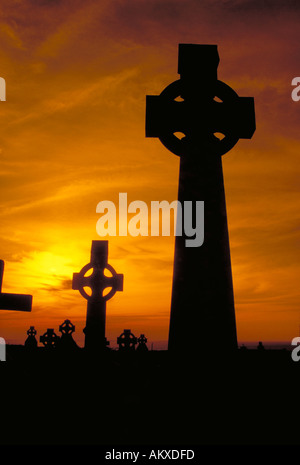 Due croci celtiche si stagliano contro golden la luce del tramonto in un antico cimitero. County Clare, Irlanda Foto Stock