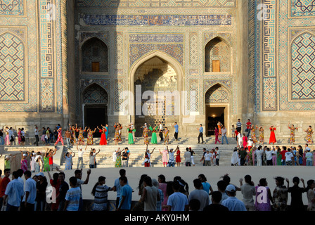 Giovani donne che danzano davanti Madrasah Sherdar Registan Samarcanda Uzbekistan Foto Stock
