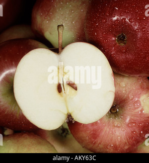 Close up di mele rosse con uno tagliate a metà con discreti goccioline di acqua sulla frutta Foto Stock