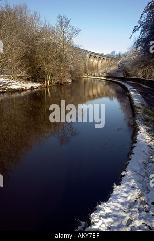 L Huddersfield stretto canale e il viadotto ferroviario a Saddleworth Uppermill con cielo blu e coperta di neve alberi e alzaia Foto Stock