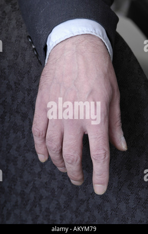 Un uomo con le mani in mano in appoggio sul suo giro in un business suit. Foto Stock