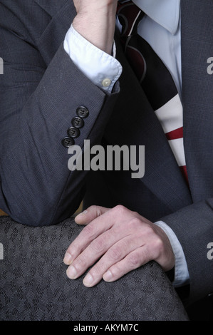 Un uomo con le mani in mano in appoggio sul suo giro in un business suit. Foto Stock