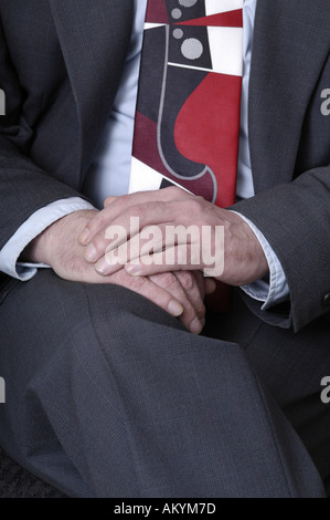 Un uomo con le mani in mano in appoggio sul suo giro in un business suit. Foto Stock