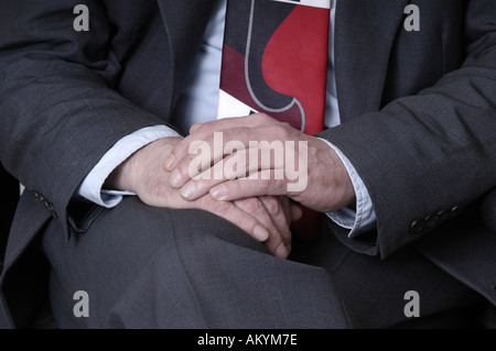 Un uomo con le mani in mano in appoggio sul suo giro in un business suit. Foto Stock