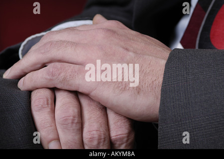 Un uomo con le mani in mano in appoggio sul suo giro in un business suit. Foto Stock