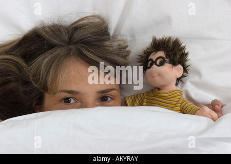 Donna con una bambola in letto Foto Stock