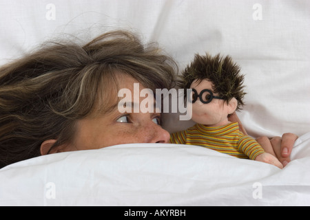 Donna con una bambola in letto Foto Stock