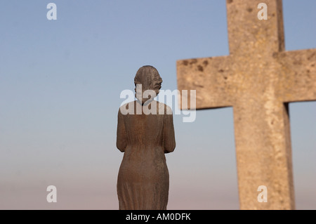 Statua di bronzo di una giovane donna e una croce in marmo visto da dietro nel cimitero Sineasca Craiova Dolj Oltenia Romania Foto Stock