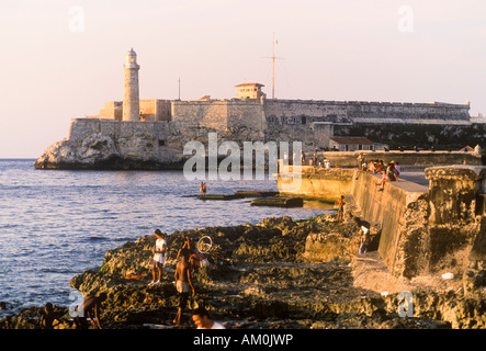 I pescatori locali lungo il famoso Malecon sul lungomare nella Vecchia Città dell Avana con el Morro fortezza Foto Stock