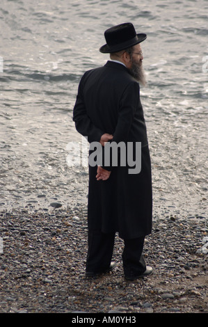 Di mezza età nigun ortodosso ebreo sulla vacanza annuale vacanza a Aberystwyth in piedi vicino al mare Foto Stock