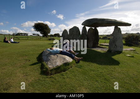 Persone rilassante sulle pietre a Pentre Ifan neolitico Età della pietra tumulo Newport Pembrokeshire Wales UK Foto Stock
