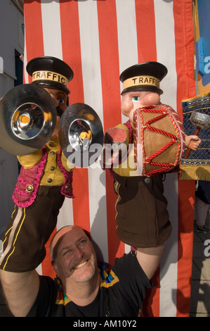 Un burattinaio tenendo in mano due marionette in veste di suonare musica traffico operai, Aberystwyth Wales UK Foto Stock