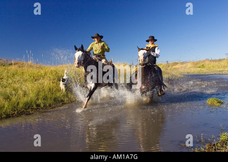 Cowgirl e cowboy a cavallo in acqua, Oregon, Stati Uniti d'America Foto Stock