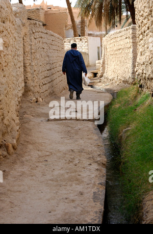 Local uomo cammina attraverso gli stretti vicoli della città vecchia di Ghadames, Libia Foto Stock