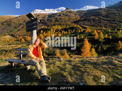 Escursionista in appoggio su una panca in legno nel paesaggio autunnale, Tirolo orientale, Austria Foto Stock