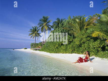 Geografia / viaggi, Maledives, Kuda Huraa Island, donna in abito rosso è seduto sulla spiaggia sabbiosa, Additional-Rights-Clearance-Info-Not-Available Foto Stock