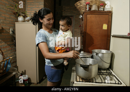 Donna con bambino cottura, 'Comunidad 18 de Agosto", Paraguay, Sud America Foto Stock