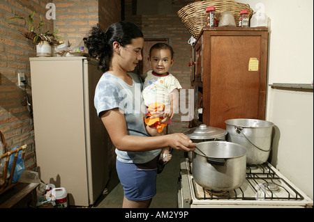 Donna con bambino cottura, 'Comunidad 18 de Agosto", Paraguay, Sud America Foto Stock