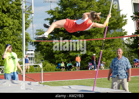 Ragazza adolescente pole vaulter deselezionando la barra in una scuola di via e il quartiere di campo soddisfare Foto Stock