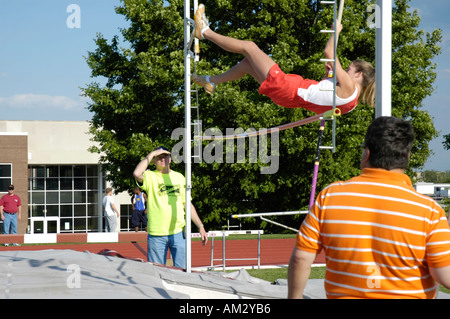 Ragazza adolescente pole vaulter deselezionando la barra in una scuola di via e il quartiere di campo soddisfare Foto Stock