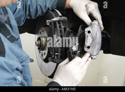 Mechanic il montaggio delle nuove pastiglie dei freni per auto in officina Foto Stock