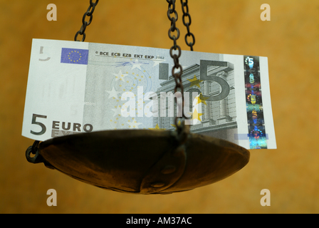 Scala con un peso di cinque di banconote in euro. Foto Stock