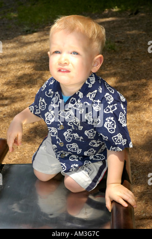 Giovane ragazzo toddler salendo dal fondo di un parco giochi slitta Foto Stock