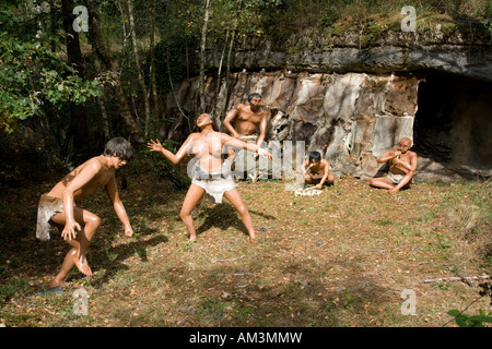 Famiglia CroMagnon dancing celebrando con la pelle Riparo coperto e primitiva di suonare strumenti musicali Dinosaur Park Francia Foto Stock