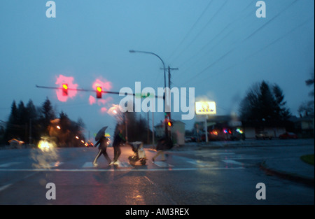 Vista attraverso un parabrezza bagnato di una famiglia che attraversa la strada a una serata piovosa a Everett, Washington, Stati Uniti Foto Stock